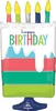 A pink, blue, and green tiered cake that has candles coming from the top and it says happy birthday